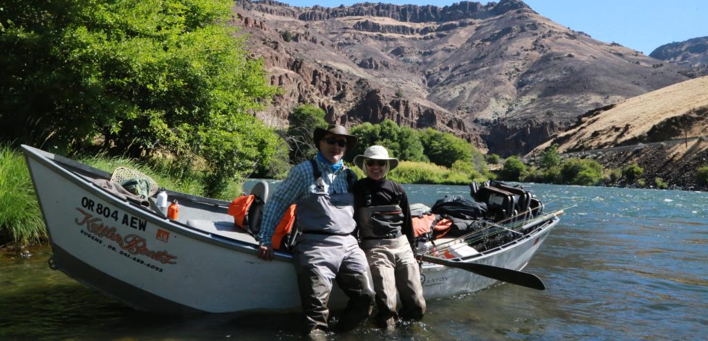 A pair of anglers takes a break from some incredible fishing for the native-Redband rainbows and legendary steelhead that inhabit these waters, while resting against their loaded drift boat during a sunny summer day on the Lower Deschutes river.